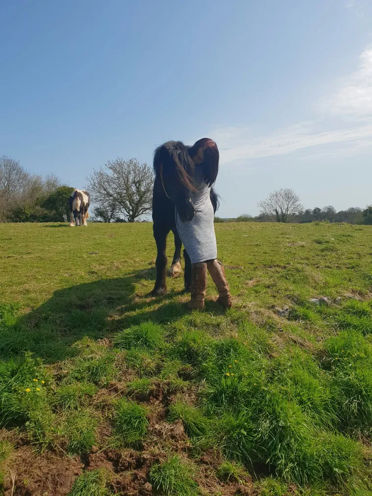 Amber in the field with her arms round one of her cobs