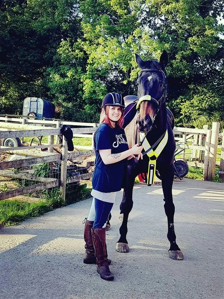 Amber holding one of her horses on the yard on a summer evening